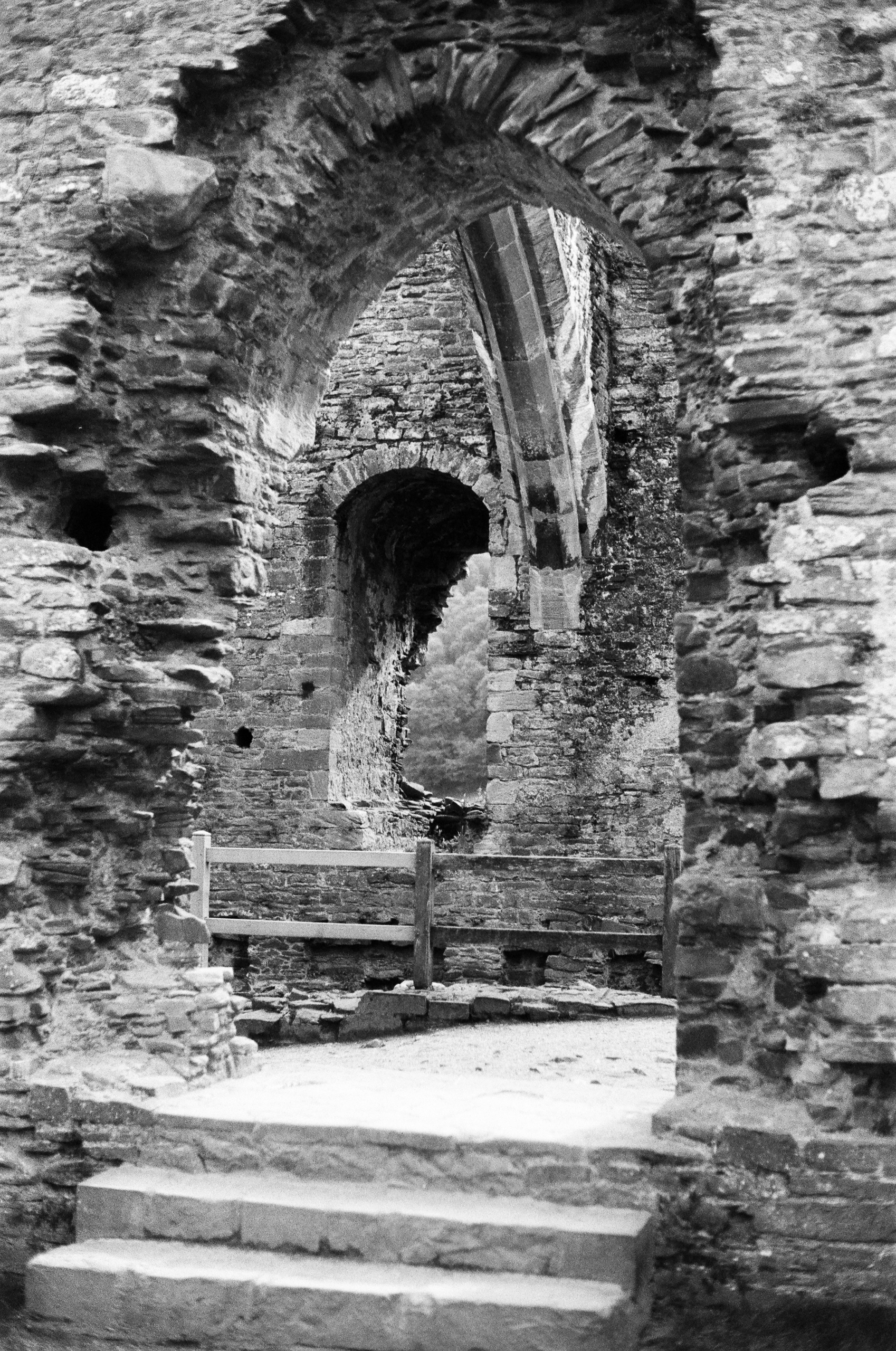 Stone steps lead through a series of arched openings in a ruined stone building.