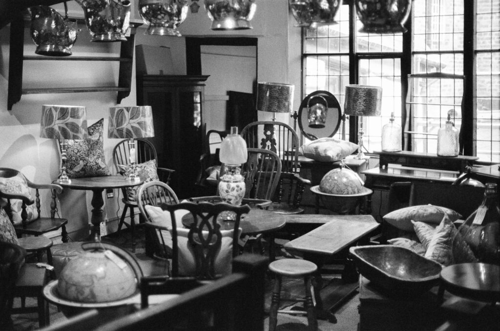 An antique shop filled with wooden chairs, tables, lamps, and globes.