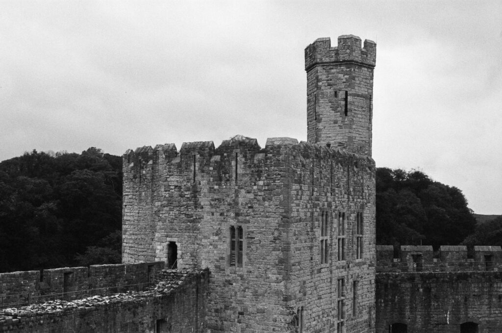 A stone castle with a prominent tower and crenellated battlements against a cloudy sky.