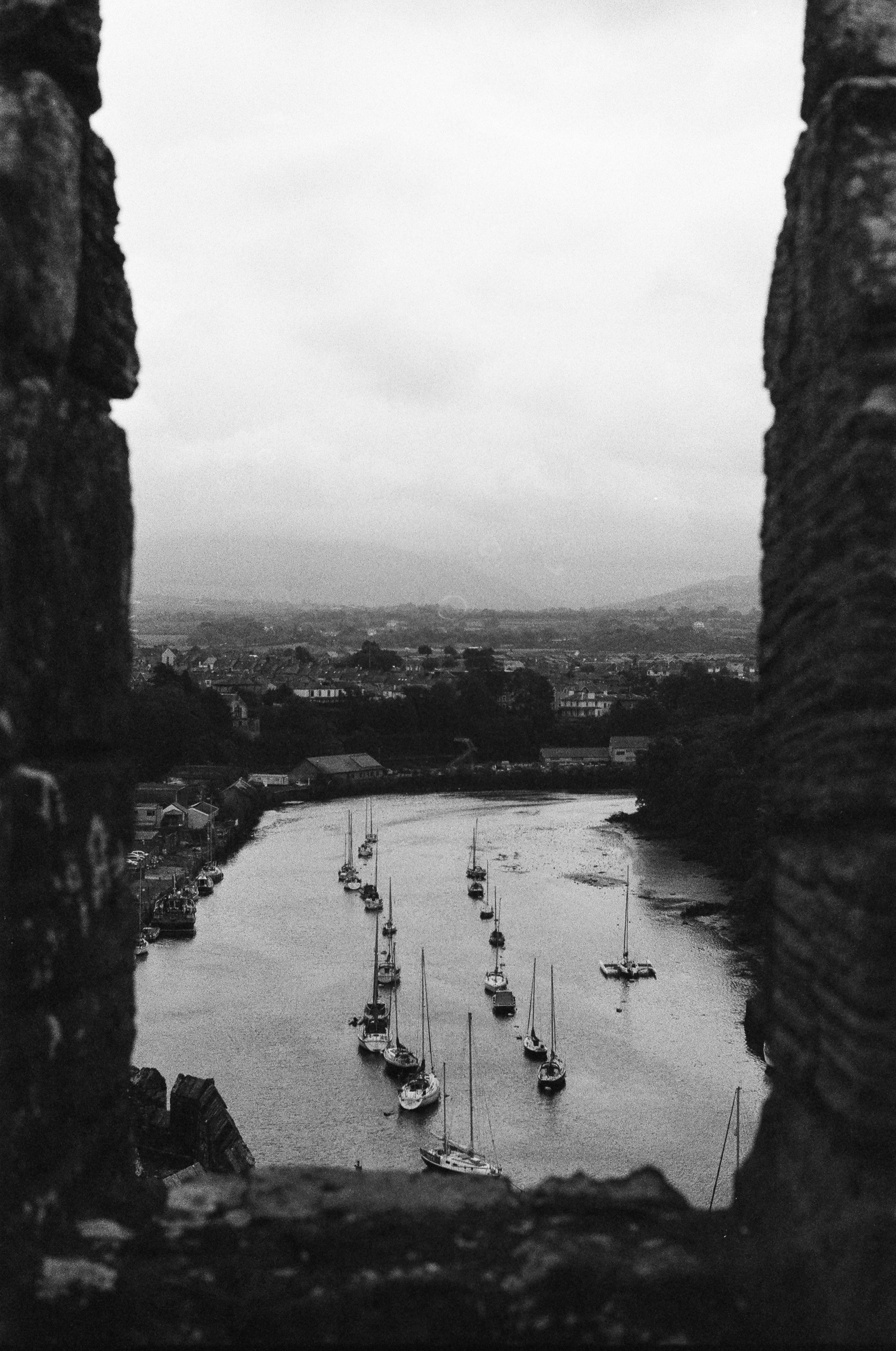 View of a river filled with sailboats, seen through a stone archway.